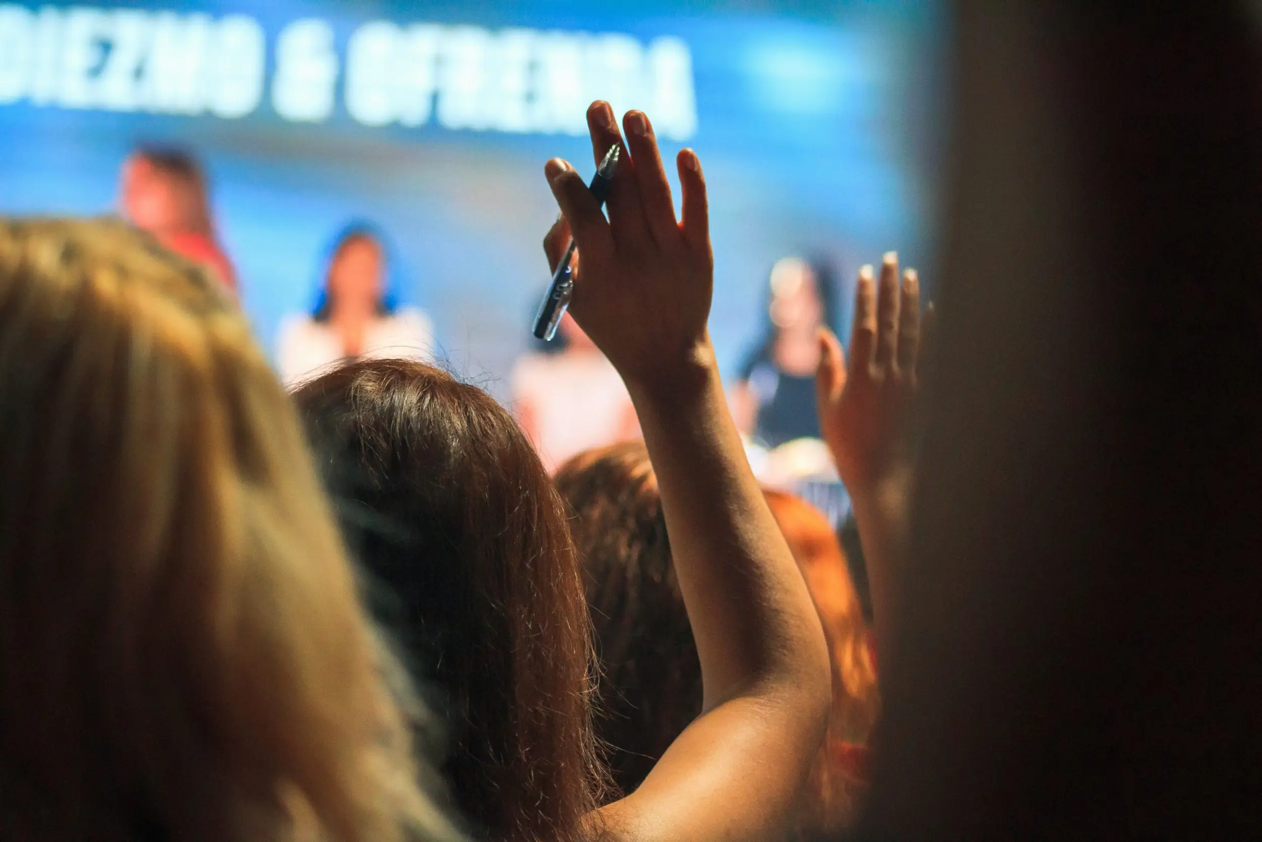 An enthusiastic audience member raises their hand to engage during a sales presentation, highlighting the importance of concluding with a compelling call-to-action that is typical of a high-impact sales deck